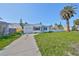 Charming single-story home featuring a well-maintained front yard and a mature palm tree under a clear blue sky at 15548 1St E St, Redington Beach, FL 33708