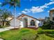 Charming single-story home featuring a well-manicured lawn, a two-car garage, and eye-catching white and orange trim at 1609 Shady Oaks Dr, Oldsmar, FL 34677