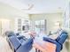 Bright living room features a ceiling fan, blue couches, and sliding glass doors to the pool at 1609 Shady Oaks Dr, Oldsmar, FL 34677