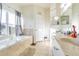 Bright bathroom featuring a soaking tub beneath a window, double sinks, and a tiled floor for a spa-like feel at 18012 Melibee Stone St, Tampa, FL 33647