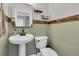 Charming powder room with pedestal sink, wood-trimmed walls, and decorative shelves at 219 126Th Ave, Treasure Island, FL 33706