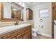 Bathroom featuring a wood vanity with quartz countertops, decorative mirror, and tiled shower at 29307 Schinnecock Hills Ln, San Antonio, FL 33576