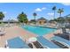 Relaxing community pool area featuring lounge chairs and shady umbrellas under a clear, sunny sky at 29307 Schinnecock Hills Ln, San Antonio, FL 33576