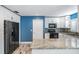 Modern kitchen featuring white cabinets, granite counters, black appliances, and a blue accent wall at 29307 Schinnecock Hills Ln, San Antonio, FL 33576