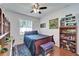 Cozy bedroom featuring a ceiling fan, window with blinds, bed with blue bedding, and display shelves at 3822 Salida Delsol Dr, Sun City Center, FL 33573