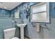 Stylish blue bathroom featuring a pedestal sink, retro tile, and a decorative mirror at 472 Pine St, Tarpon Springs, FL 34689