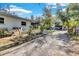 A large driveway with side yard featuring tropical plants leads to a charming house and entertaining area at 472 Pine St, Tarpon Springs, FL 34689