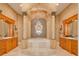 Luxurious bathroom featuring dual vanities, columns, a chandelier, and a soaking tub at 4873 Quill Ct, Palm Harbor, FL 34685