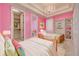 Charming bedroom with bright pink walls, built-in shelves, and a stylish chandelier at 4873 Quill Ct, Palm Harbor, FL 34685