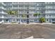 Condominium building entrance features palm trees, tropical plants, and visitor parking at 5925 Shore S Blvd # 406, Gulfport, FL 33707