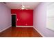 Bright bedroom featuring red accent wall, hardwood floors, and a ceiling fan at 6222 Kingbird Manor Dr, Lithia, FL 33547