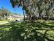 Spacious yard of this residence with mature trees casting shadows over the lawn at 6222 Kingbird Manor Dr, Lithia, FL 33547