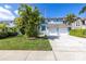 Charming two-story home with a two-car garage, tropical landscaping, and an American flag flying overhead at 7284 Pebble Beach Ln, Seminole, FL 33777