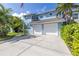 Charming two-story home showcasing a well-manicured lawn, a driveway, and mature palm trees at 7284 Pebble Beach Ln, Seminole, FL 33777