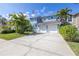 Charming two-story home showcasing a well-manicured lawn, a driveway, and mature palm trees at 7284 Pebble Beach Ln, Seminole, FL 33777