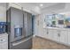 A kitchen featuring a stainless steel refrigerator, white cabinets, and a view of the living area at 7284 Pebble Beach Ln, Seminole, FL 33777