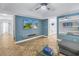 Bright living room features blue accent walls, a ceiling fan, and neutral tile flooring at 7284 Pebble Beach Ln, Seminole, FL 33777