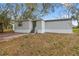 Exterior view of home with gray siding and front door, landscaped front yard at 8408 Bob Wiggs Ave, Lithia, FL 33547