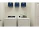 White front load washer and dryer with blue storage containers on the shelf above them at 9312 Cannon Beach Dr, Parrish, FL 34219