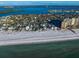 Aerial view of beachfront homes with direct access to the sandy beach and ocean, complemented by nearby high-rise buildings at 939 Mandalay Ave, Clearwater Beach, FL 33767