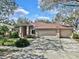 Attractive single-Gathering home featuring a well-maintained lawn, a three-car garage, and mature landscaping at 140 Sage Cir, Crystal Beach, FL 34681
