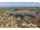 Picturesque aerial shot of a neighborhood bordering a lake, showcasing homes and natural beauty under a cloudy blue sky at 1472 Ivydale Rd, Spring Hill, FL 34606