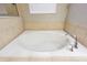 A close-up view of a large, tiled bathtub featuring chrome hardware and a window with blinds at 2111 Roanoke Springs Dr, Ruskin, FL 33570