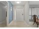 Inviting foyer with white door, wood floors, soft blue accent wall, and dining area at 710 Treasure Boat Way, Sarasota, FL 34242