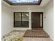 Welcoming front entrance with a brown door, tile steps, adjacent window, and landscaped pebbles at 710 Treasure Boat Way, Sarasota, FL 34242