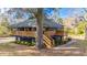 Charming raised home with a wooden deck, staircase, mature trees, and landscaped yard at 8204 Stoner Rd, Riverview, FL 33569
