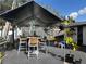 Backyard under a tent cover, featuring an outdoor table, chairs, storage units, and a small grassy area at 8706 N Boulevard, Tampa, FL 33604