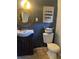 Charming half bath featuring dark walls, a round mirror, an elegant light fixture, and unique decor elements at 8706 N Boulevard, Tampa, FL 33604