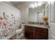 Bathroom with floral shower curtain, granite countertop, and wooden cabinets at 1002 Vineyard Ln, Oldsmar, FL 34677