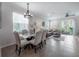 Bright dining and living area featuring tiled floors, a chandelier, a ceiling fan, and a sliding glass door to the backyard at 1002 Vineyard Ln, Oldsmar, FL 34677