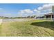 Large grassy backyard, enclosed by a white fence, with views of neighboring houses and a blue sky at 11938 Bahia Valley Dr, Riverview, FL 33579