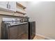 Modern laundry room featuring front loading washer and dryer with storage shelving at 11938 Bahia Valley Dr, Riverview, FL 33579