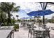 Outdoor seating with blue umbrellas surrounding a community pool with tables and chairs at 12316 49Th E St, Parrish, FL 34219