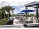 Outdoor seating with blue umbrellas surrounding a community pool with tables and chairs at 12316 49Th E St, Parrish, FL 34219