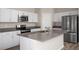 Well-lit kitchen featuring stainless steel appliances, white cabinets, island with gray countertop and breakfast bar at 13022 Wellspring Dr, Lithia, FL 33547