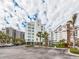 Exterior view of condo buildings, palm trees and parking area under a partly cloudy sky at 1590 Gulf Blvd # 501, Clearwater Beach, FL 33767