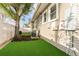 Side backyard featuring an artificial lawn, tree, utilities, and a white fence at 1924 W Carmen St, Tampa, FL 33606