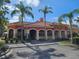 Community clubhouse with attractive architecture, tropical landscaping, and visitor parking at 2755 Via Capri Dr # 1215, Clearwater, FL 33764