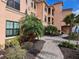 Exterior of a well-maintained building with meticulous landscaping, palm trees, and a brick walkway at 2755 Via Capri Dr # 1215, Clearwater, FL 33764