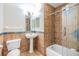 Bathroom featuring brown tile walls, pedestal sink, and a glass-enclosed shower/tub at 2786 Countryside Blvd # 2, Clearwater, FL 33761