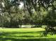 Expansive backyard with mature trees and a picturesque view of a tranquil pond at 29318 Whipporwill Ln, Wesley Chapel, FL 33543