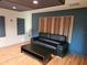 Modern living room featuring wood paneling, a black sofa, and a sleek coffee table at 29318 Whipporwill Ln, Wesley Chapel, FL 33543