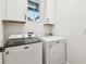 Well-lit laundry room featuring a modern washer and dryer, storage cabinets, and a window at 310 Blackrock Ln, Apollo Beach, FL 33572