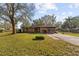 Brick home with a driveway, mature trees, and manicured lawn at 38928 Tall Dr, Zephyrhills, FL 33540