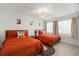 Bright bedroom with two beds featuring a geometric orange pattern, and light colored walls at 4706 Shale Pl, Tampa, FL 33615