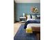 A modern bedroom with a yellow bed, a wooden bench and a blue textured wall at 4900 59Th S Ave, St Petersburg, FL 33715